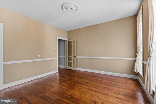 spare room featuring baseboards and hardwood / wood-style floors