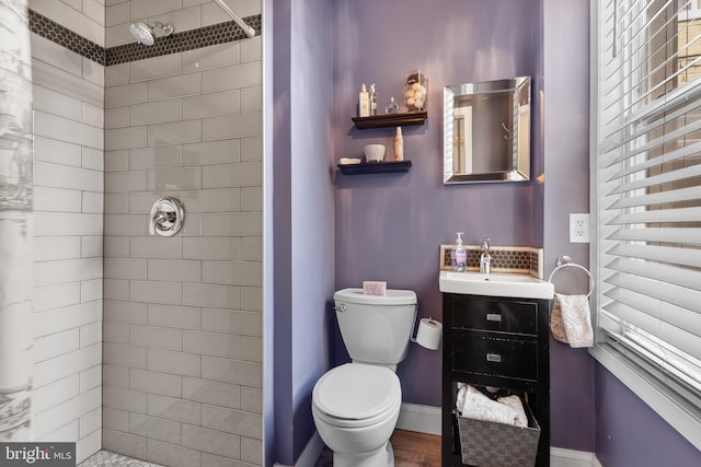 bathroom with vanity, a tile shower, and toilet