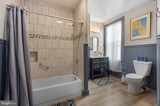 full bathroom featuring vanity, wood finished floors, toilet, a wainscoted wall, and shower / bath combo