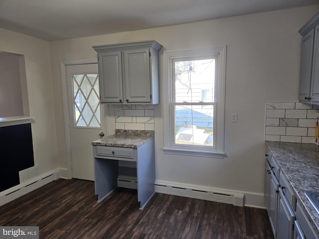 kitchen with a wealth of natural light, a baseboard heating unit, dark wood-type flooring, and gray cabinetry