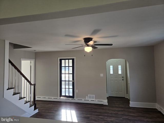 foyer featuring baseboards, dark wood finished floors, arched walkways, stairs, and baseboard heating