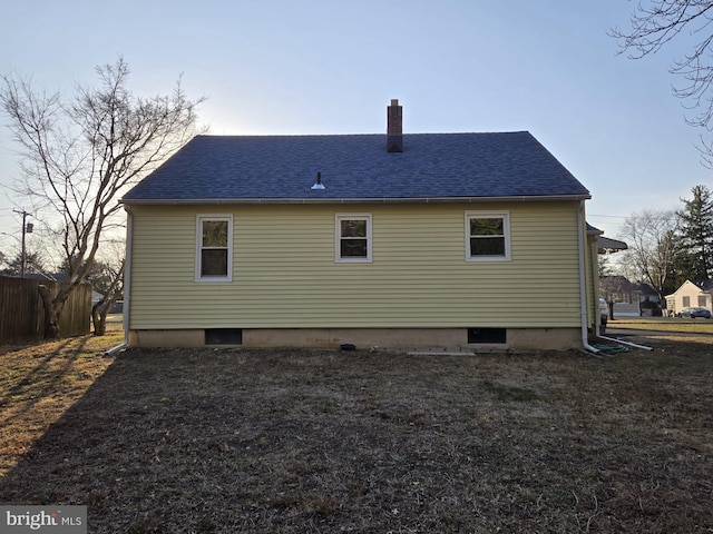 rear view of property featuring a shingled roof, fence, and a chimney