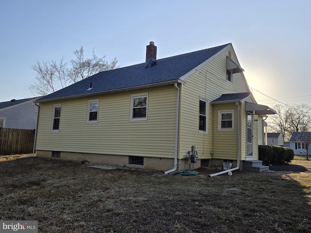 back of property with fence, roof with shingles, a yard, a chimney, and entry steps