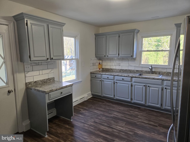 kitchen featuring gray cabinets, a sink, a baseboard heating unit, dark wood finished floors, and freestanding refrigerator