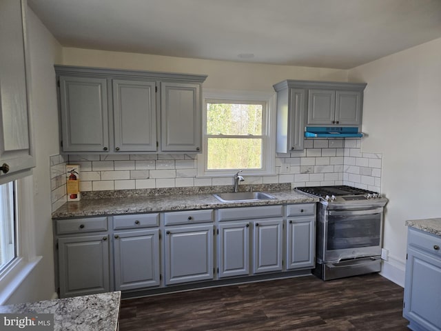 kitchen featuring stainless steel gas range oven, gray cabinets, under cabinet range hood, and a sink