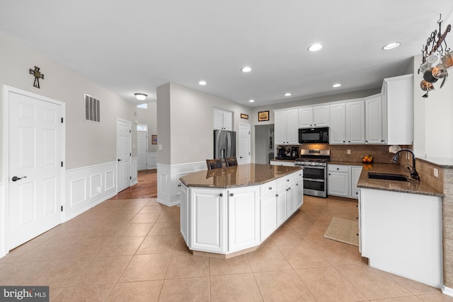 kitchen featuring a center island, light tile patterned floors, visible vents, appliances with stainless steel finishes, and a sink