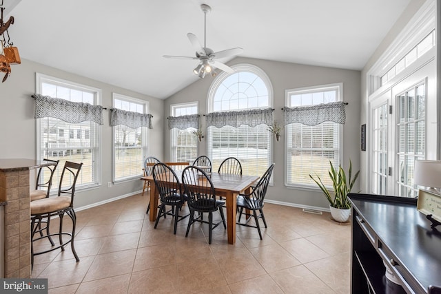 dining area featuring light tile patterned floors, vaulted ceiling, a wealth of natural light, and baseboards