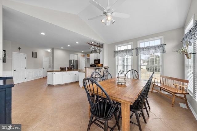 dining room featuring light tile patterned floors, ceiling fan, a decorative wall, a wainscoted wall, and visible vents