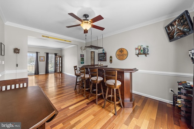 interior space featuring ornamental molding, indoor wet bar, and wood finished floors