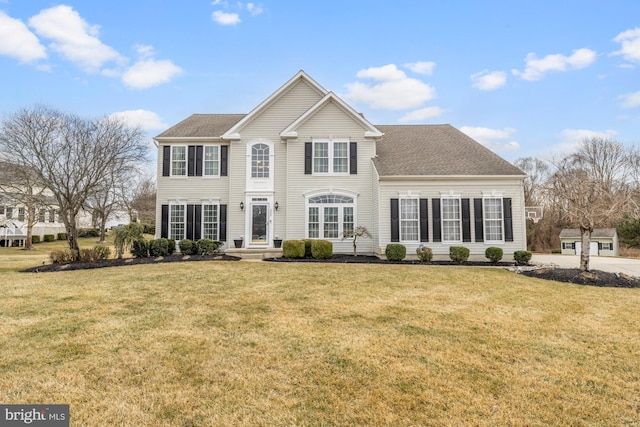 view of front facade with a front lawn and a shingled roof