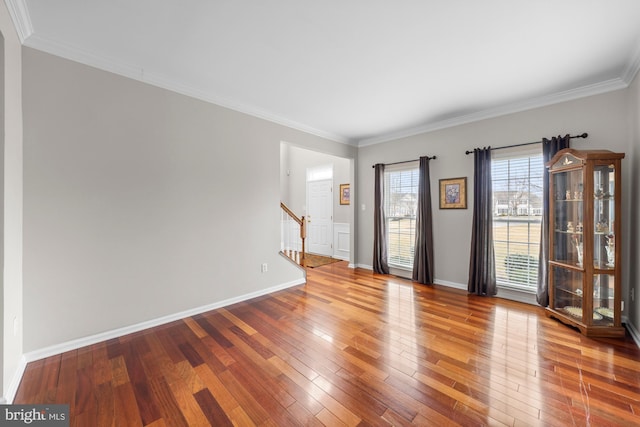 interior space featuring hardwood / wood-style flooring, crown molding, baseboards, and stairs