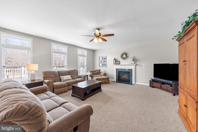 living room with a ceiling fan, a high end fireplace, light carpet, and baseboards