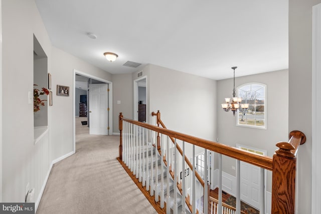 corridor featuring light carpet, baseboards, visible vents, an upstairs landing, and a chandelier