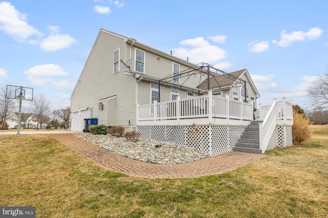 back of house with a garage, a lawn, and a wooden deck