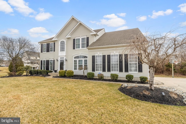 view of front of home with a shingled roof, a front yard, and driveway