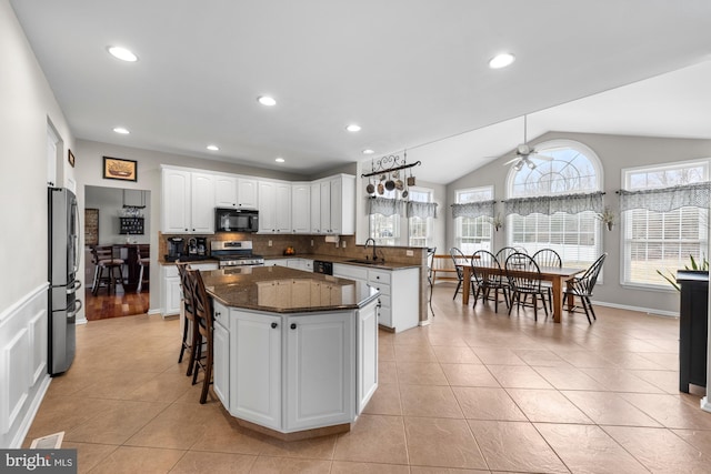 kitchen with ceiling fan, a sink, vaulted ceiling, stainless steel appliances, and backsplash