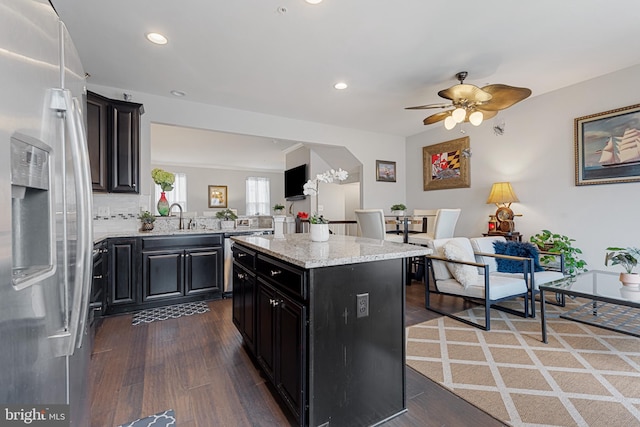 kitchen with wood finished floors, open floor plan, dark cabinetry, stainless steel refrigerator with ice dispenser, and a center island