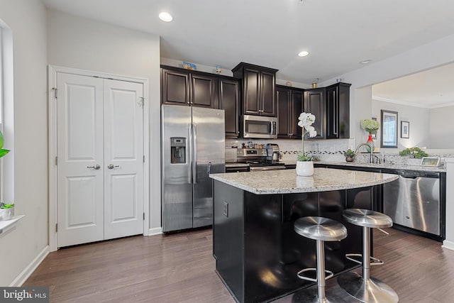 kitchen with light stone countertops, dark wood-style floors, stainless steel appliances, and decorative backsplash