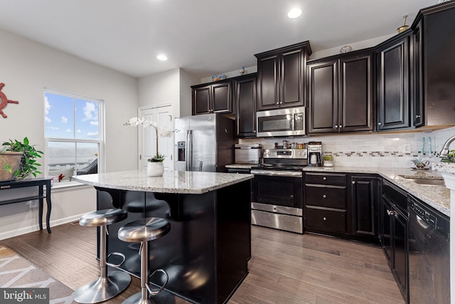 kitchen with backsplash, stainless steel appliances, wood finished floors, and a center island