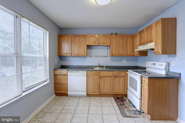 kitchen with dark countertops, under cabinet range hood, light tile patterned flooring, white appliances, and a sink