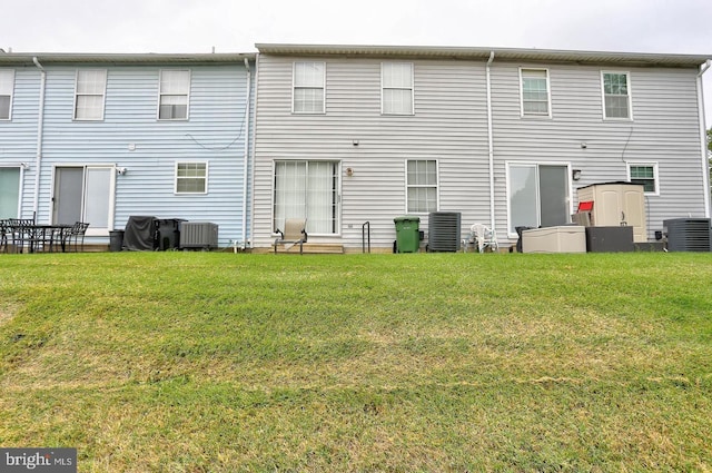 rear view of house featuring cooling unit and a yard