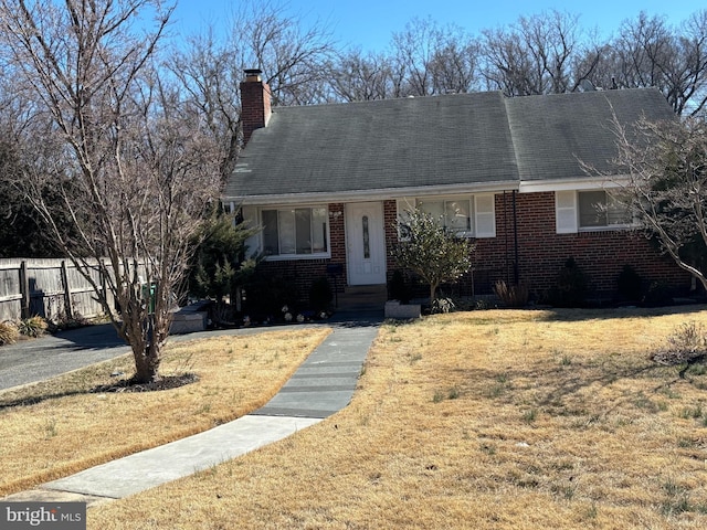 view of front of home featuring brick siding, a chimney, fence, and a front yard