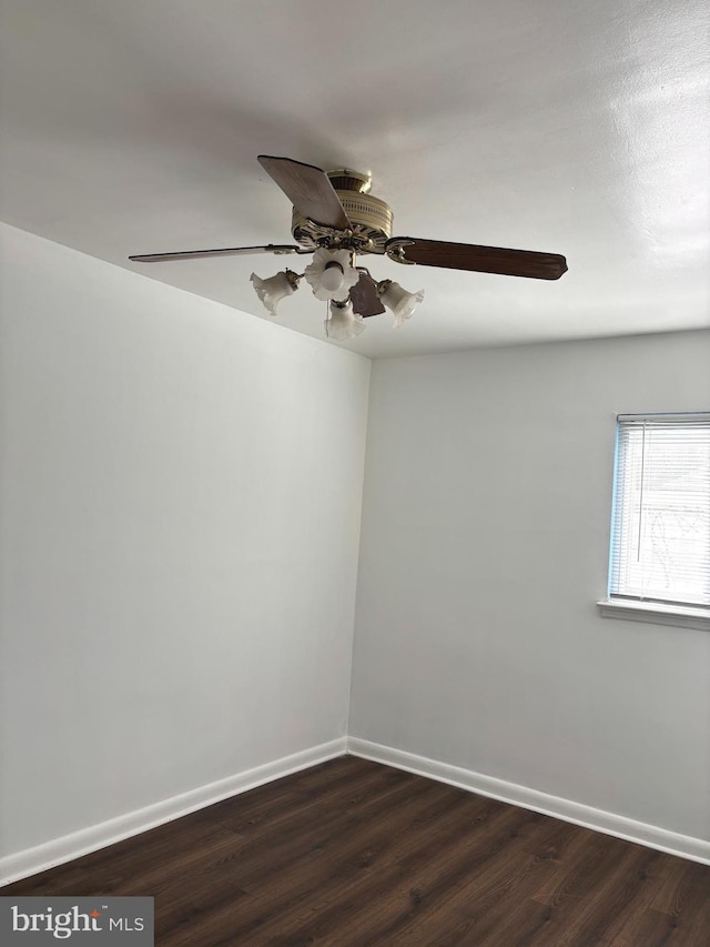 spare room with a ceiling fan, baseboards, and dark wood-type flooring