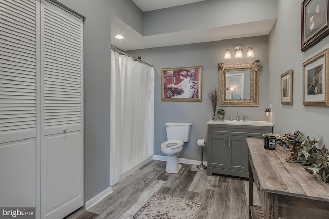 bathroom featuring baseboards, toilet, a shower with curtain, wood finished floors, and vanity