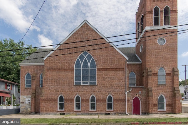 view of front facade featuring a shingled roof and brick siding