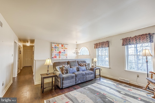 living room with a chandelier, visible vents, dark wood finished floors, and baseboards