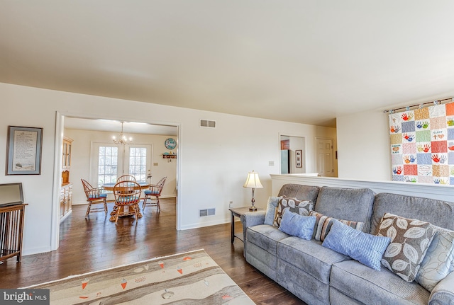 living area with visible vents, dark wood finished floors, baseboards, and an inviting chandelier