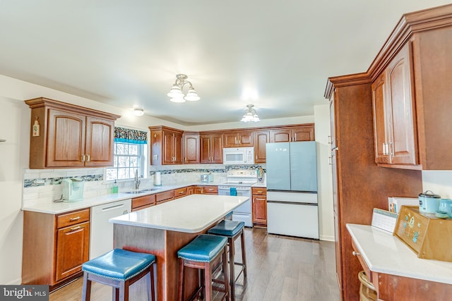 kitchen featuring light wood-type flooring, white appliances, a kitchen breakfast bar, and light countertops