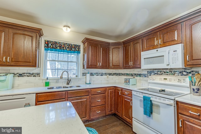 kitchen featuring light countertops, white appliances, backsplash, and a sink