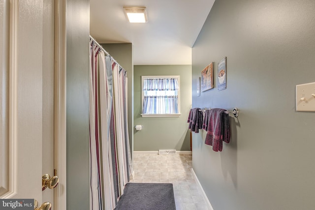 bathroom with a shower with shower curtain, visible vents, and baseboards