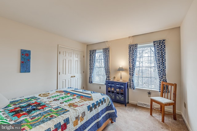 bedroom with light colored carpet, a closet, visible vents, and baseboards