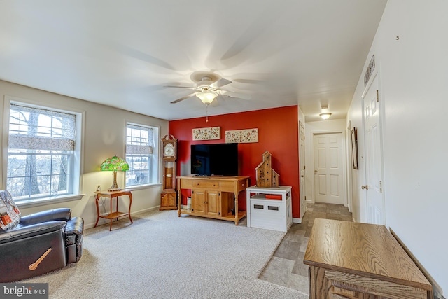 living area featuring carpet floors, ceiling fan, and baseboards