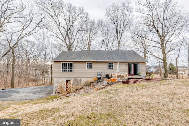 back of property with aphalt driveway and a lawn