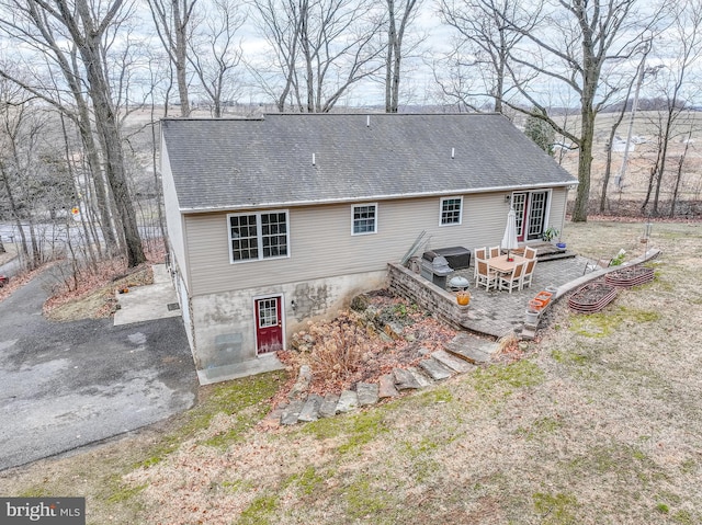 rear view of property with a shingled roof and a patio area