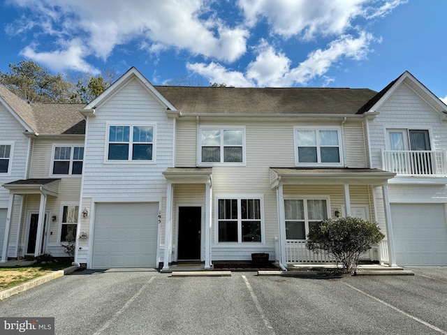 townhome / multi-family property featuring driveway, an attached garage, and a shingled roof