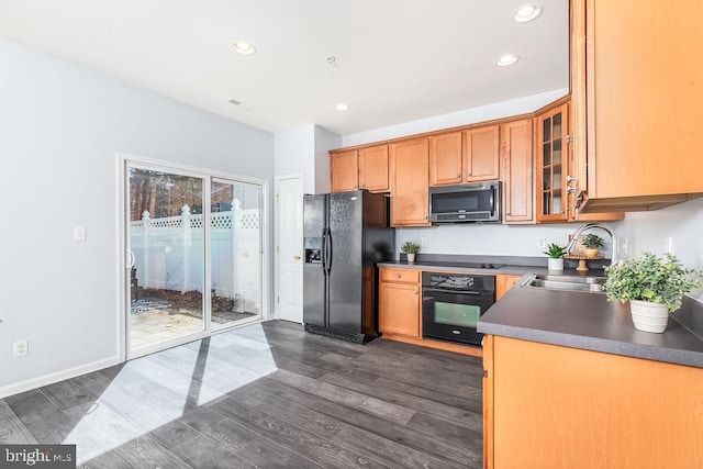 kitchen with a sink, glass insert cabinets, black appliances, and dark wood-style flooring