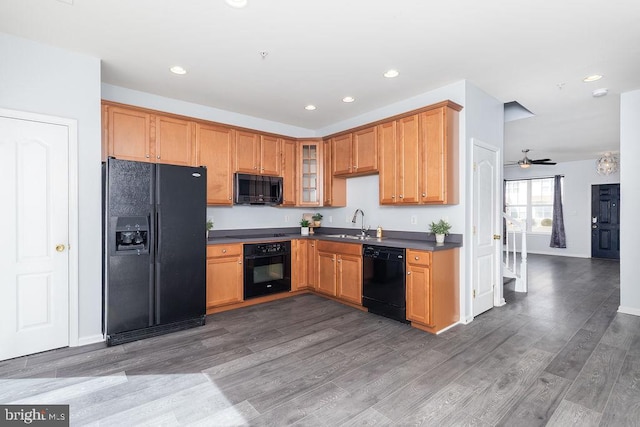 kitchen with dark countertops, glass insert cabinets, recessed lighting, wood finished floors, and black appliances