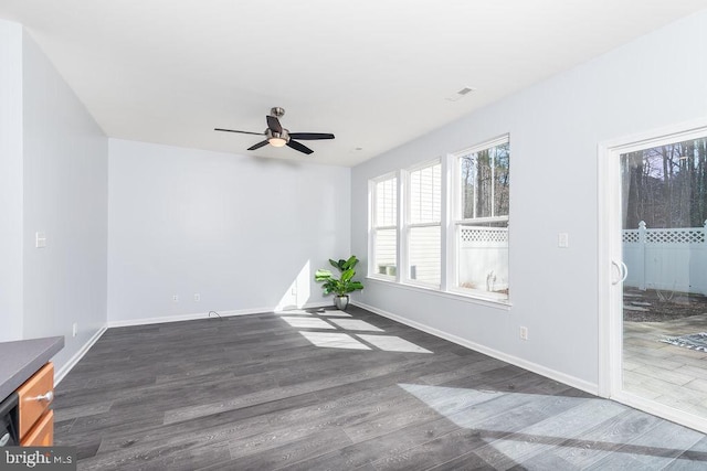 empty room featuring visible vents, a ceiling fan, baseboards, and wood finished floors