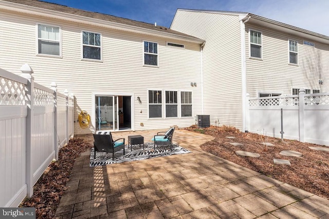 rear view of property featuring cooling unit, a patio, and a fenced backyard