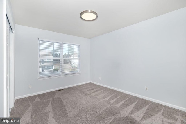 carpeted empty room featuring visible vents and baseboards