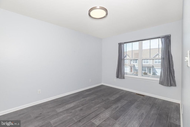 unfurnished room with dark wood finished floors, visible vents, and baseboards