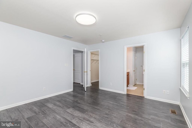 unfurnished bedroom with visible vents, baseboards, and dark wood-style floors