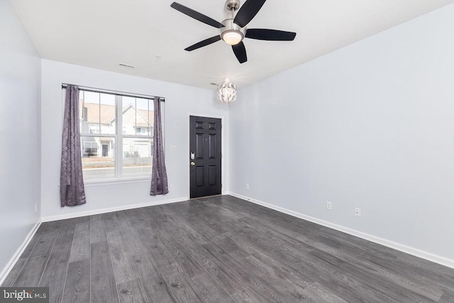 empty room featuring a ceiling fan, dark wood-type flooring, and baseboards