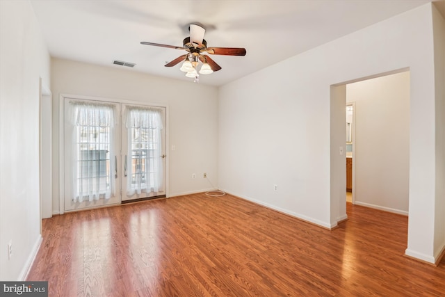 spare room with ceiling fan, wood finished floors, visible vents, and baseboards