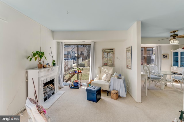 sitting room with carpet, a brick fireplace, and ceiling fan