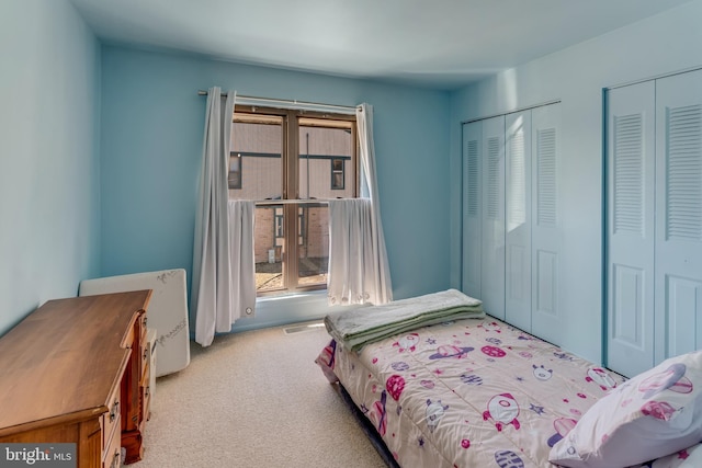 bedroom featuring visible vents, carpet flooring, and two closets